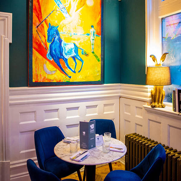 Interior view of Café Nucleus Rochester with artwork on the wall.