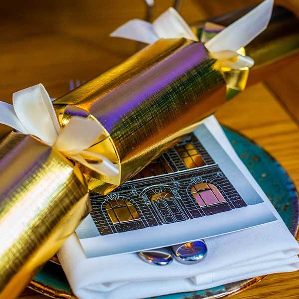 Close up image of a Christmas cracker placed on top of a Festive Afternoon Tea menu.